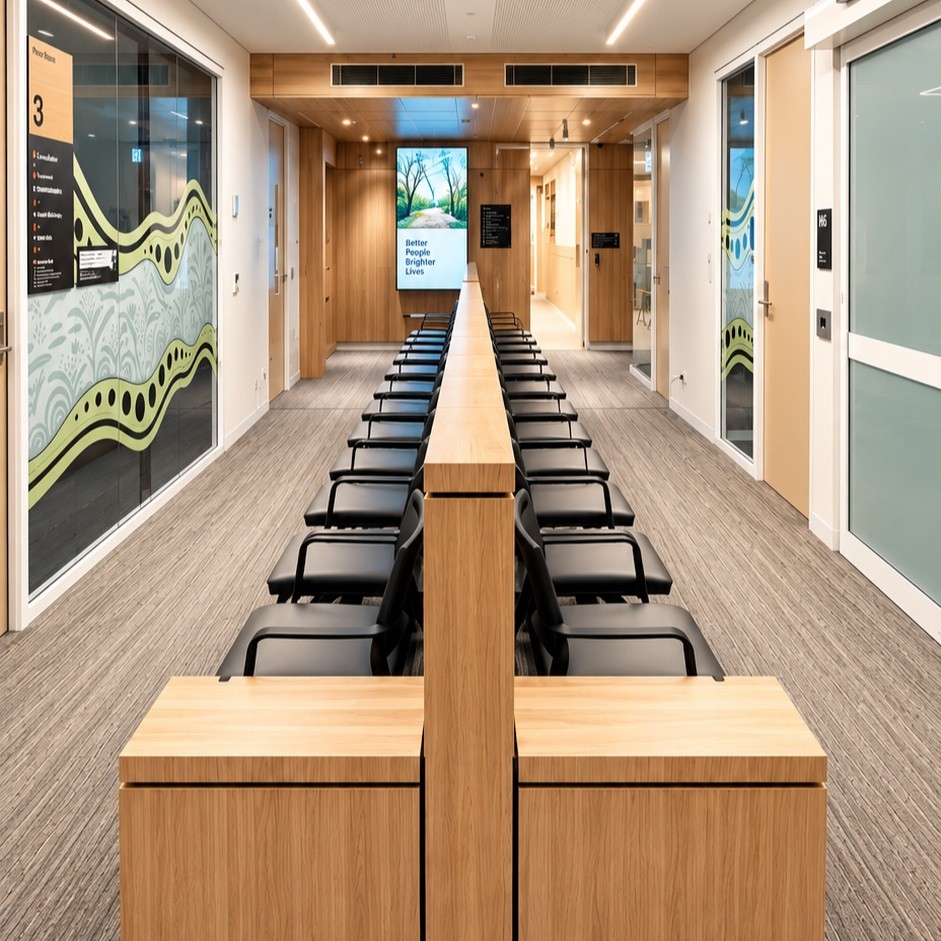 Completed commercial fit-out with a long timber joinery desk run and timber panelling down a corridor